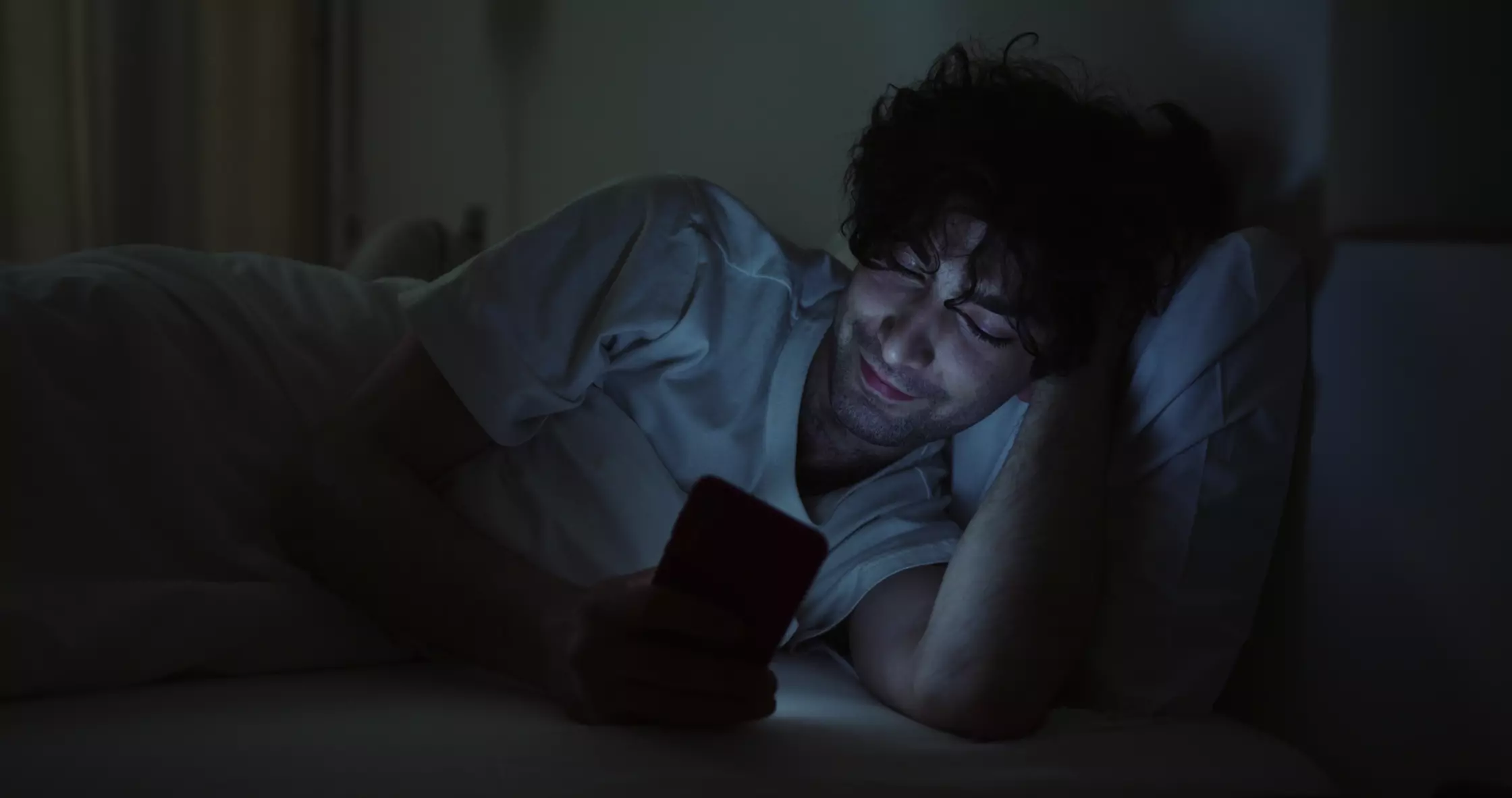A person replying to a message at night, face lit by their phone